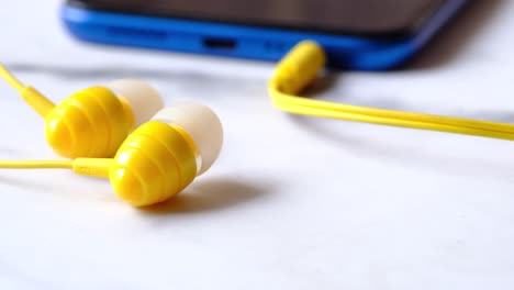 yellow earbuds connected to blue smartphone