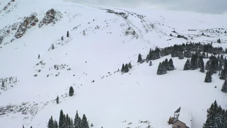 thick snow-covered mountain slopes with isolated cottage in winter park of colorado