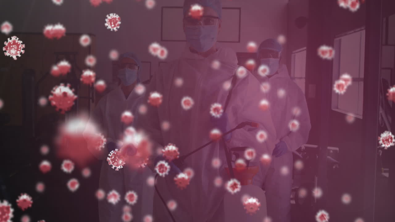 체육관에서 소독제 스프레이어를 들고 있는 의료 종사자 그룹에 여러 개의 코로나19 세포가 있습니다.