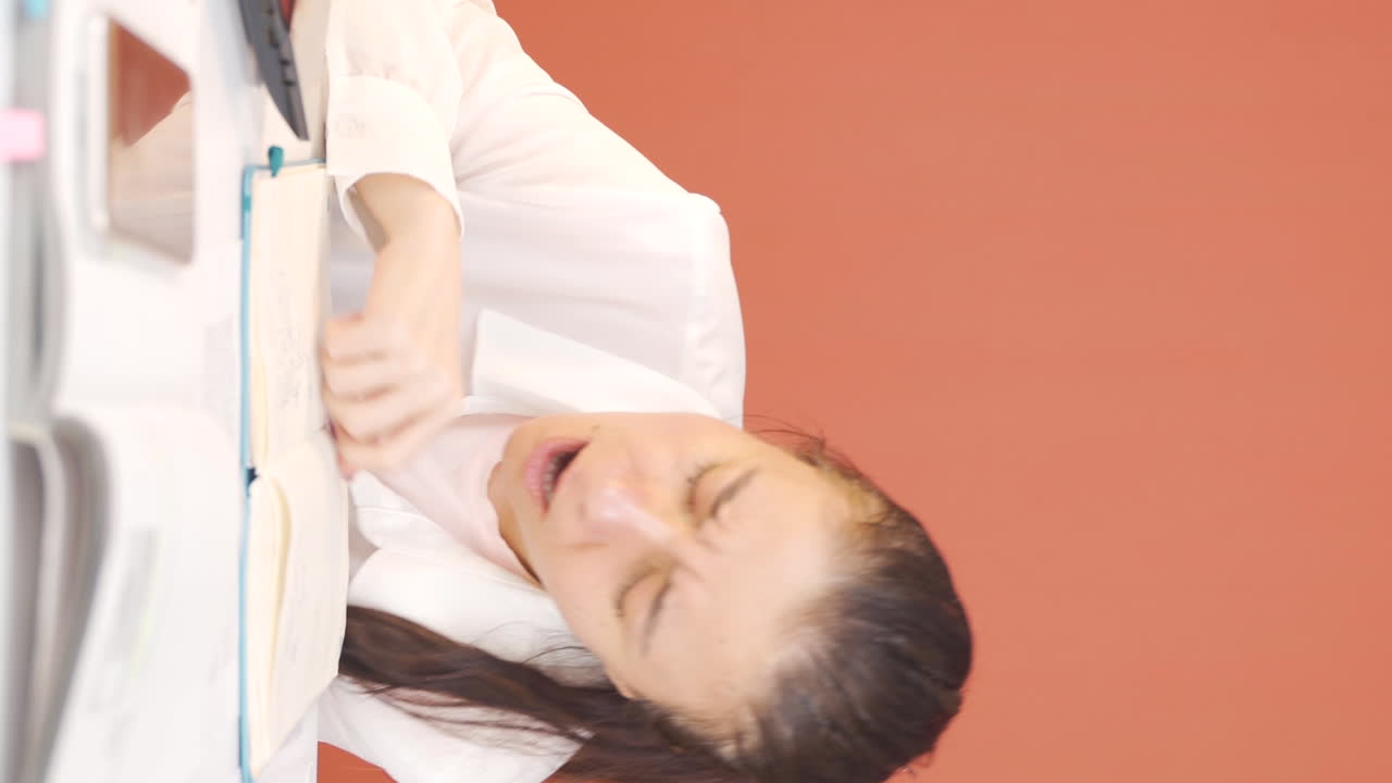 노트북 앞에서 잠들어 있는 여성의 수직 비디오입니다.