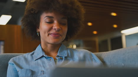 Close-Up-Of-Businesswoman-In-Modern-Open-Plan-Office-Working-On-Laptop-In-Casual-Seating-Area