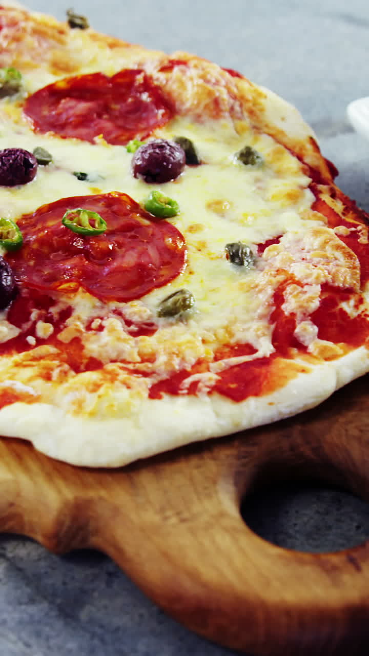 Pizza al forno con olive e peperoni servita su tagliere