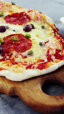 pizza al horno con aceitunas y peperoni servida en una tabla de cortar