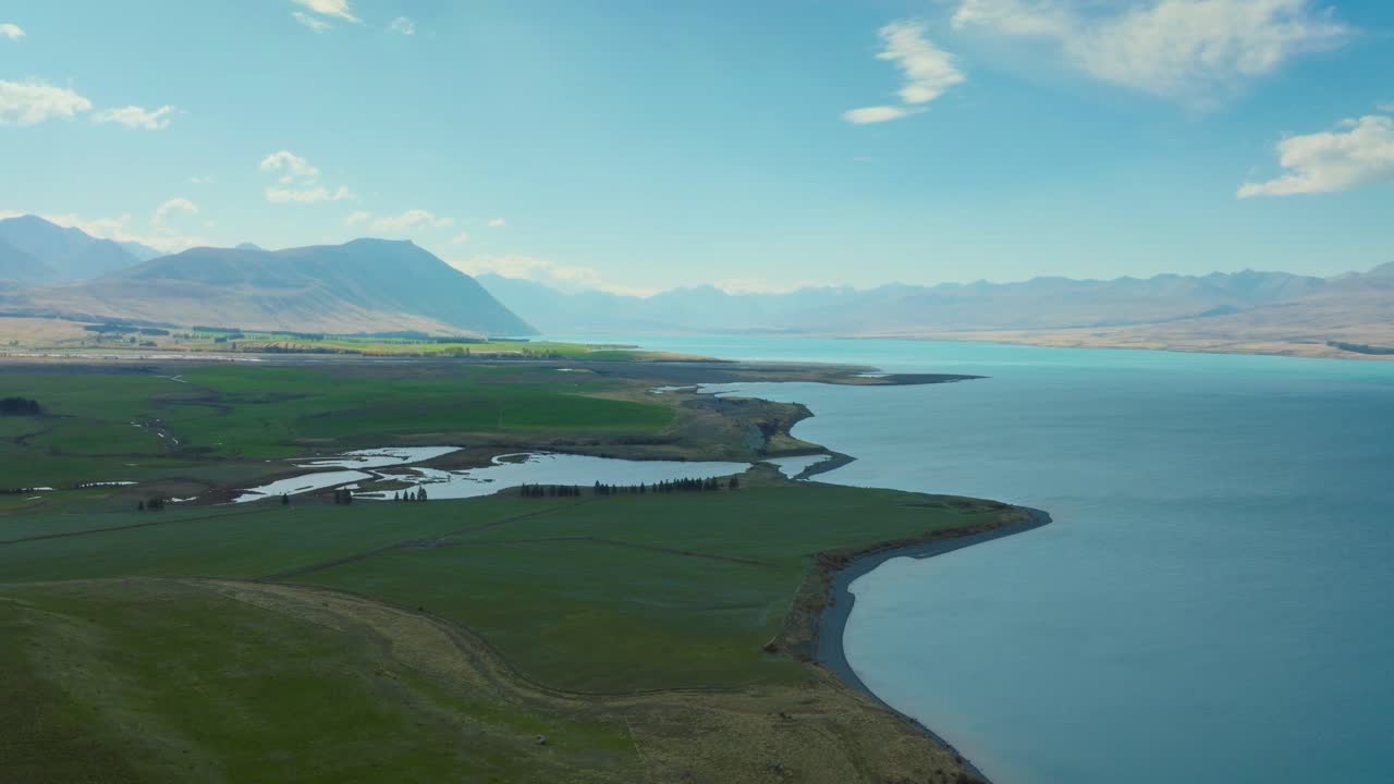 panorámica vista aérea del hermoso y remoto lago tekapo rodeado de terreno montañoso en la cuenca de mackenzie de canterbury, nueva zelanda aotearoa