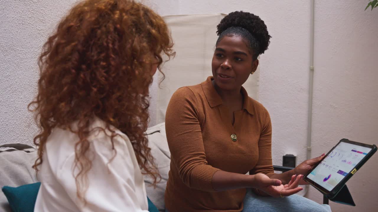 Two women collaborating on business analytics using a tablet