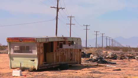 an abandoned trailer sits in the middle of the mojave desert