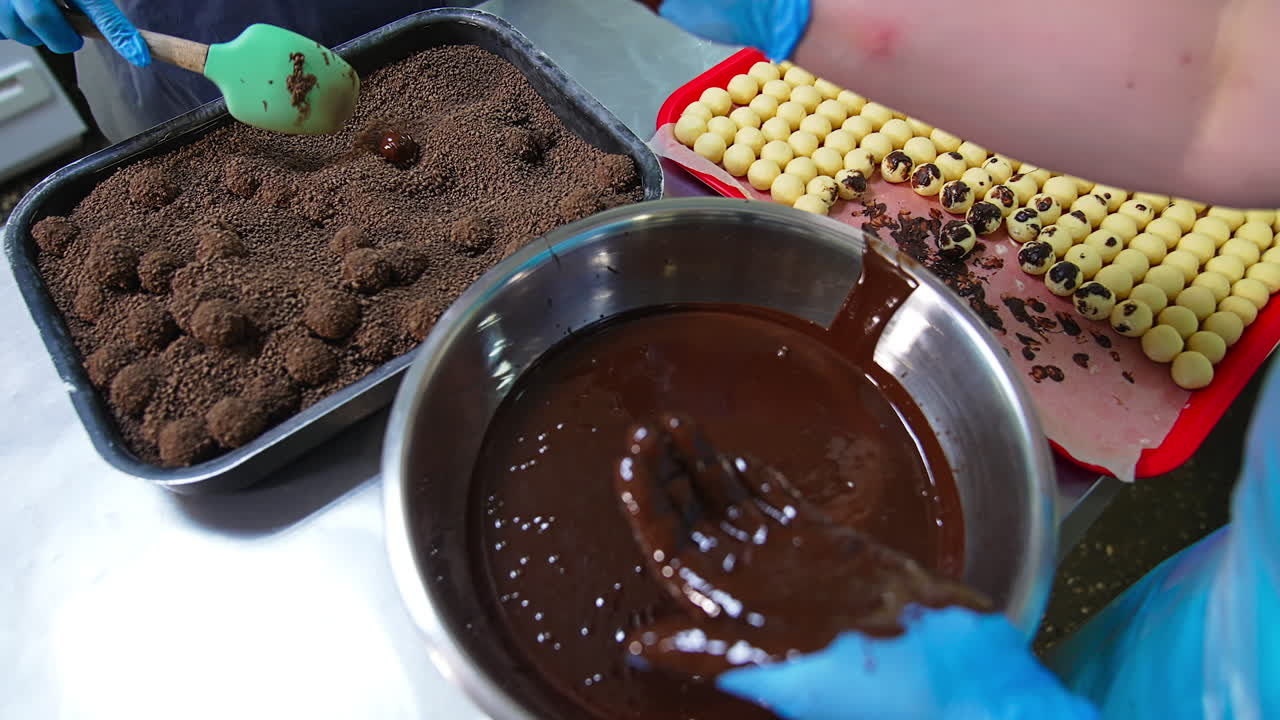 Coating sweets with chocolate and then with cocoa sprinkling. Handicraft manufacturing of chocolate desserts. Close up.