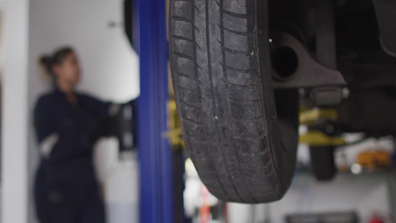 mecánica levantando un coche con una grúa automática presionando un botón en una estación de servicio de coches