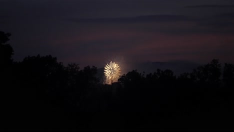 Los-Fuegos-Artificiales-Estallan-Y-Explotan-Esparciendo-Un-Resplandor-De-Color-Amarillo-A-Naranja-En-Cámara-Lenta-Durante-La-Noche.