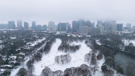 aerial push in on a snow covered piedmont park and midtown atlanta, georgia.