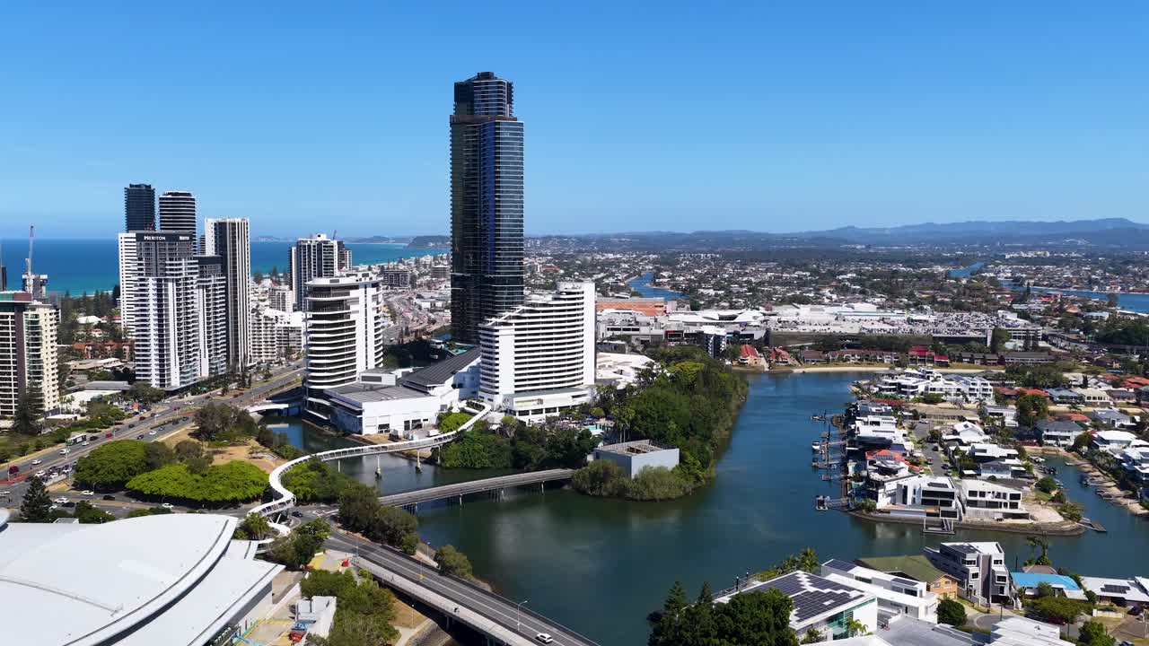 Daytime drone footage gliding above river, modern skyscrapers, residential areas, and blue sky