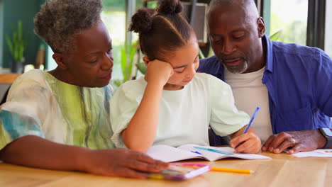 multi-generation family with grandparents helping granddaughter with school homework at home