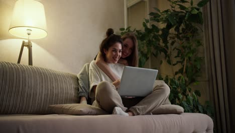 Happy-girls-friends-or-lesbians-using-laptop,-surfing-internet-together-at-home
