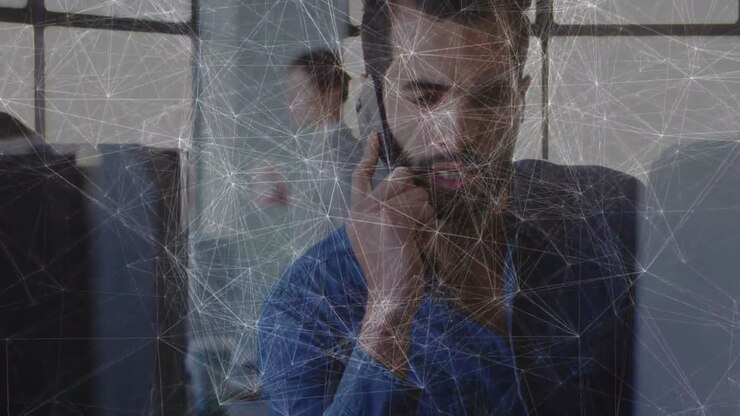 Uomo che alza il telefono, conducendo una chiamata di lavoro per un aggiornamento, con un overlay web che traccia un link al monitor.