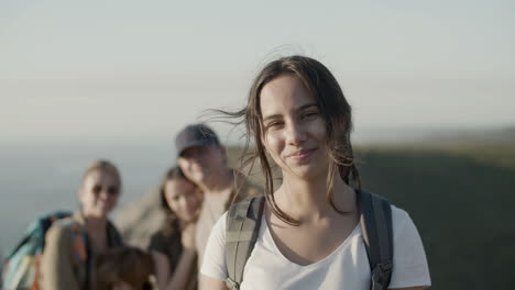 smling hiker girl looking at the camera while her family standing behind in a blurred background