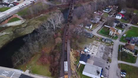 Vista-Aérea-Siguiendo-El-Tren-Industrial-Que-Viaja-A-Través-Del-Idílico-Barrio-Otoñal-De-Logansport,-Indiana.