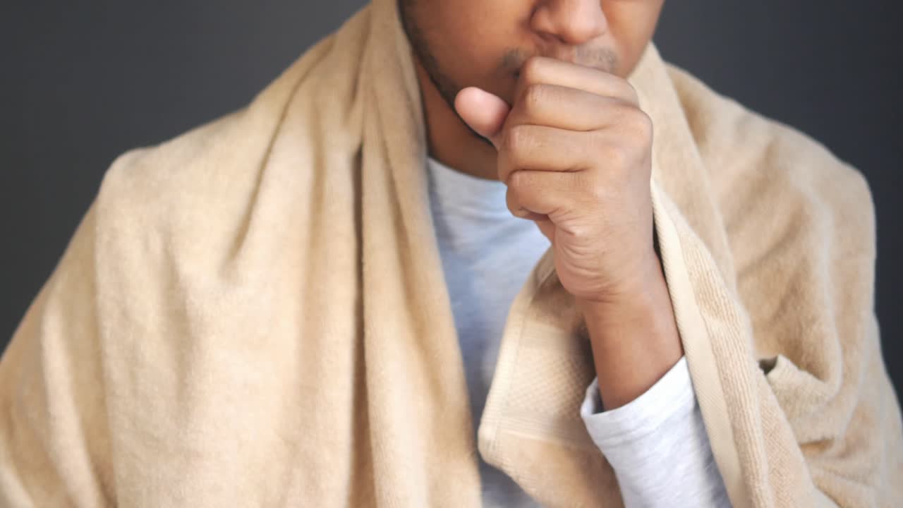 hombre tosendo en la mano, cubierto con una toalla