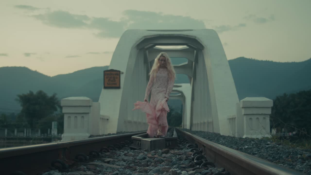 Woman in Pink Lace Dress Walking on Railway Tracks Bridge