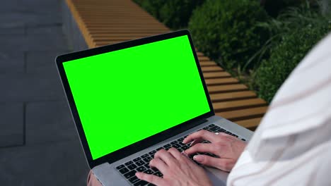 mujer freelance que trabaja al aire libre, usando una computadora portátil de pantalla verde