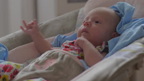 Baby-girl-lying-in-bouncy-seat-and-posseting