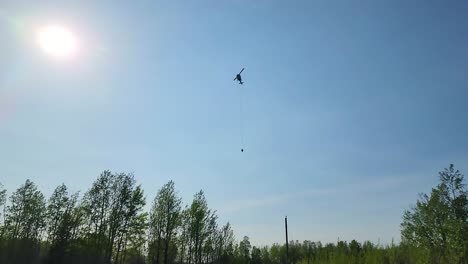 Helicóptero-De-Bomberos-En-El-Helicóptero-De-La-Fuerza-Aérea-Del-Cielo-Que-Obtiene-Agua-De-Un-Lago-De-Estanque,-Ayuda-A-Los-Bomberos-A-Extinguir-Un-Extenso-Incendio-Forestal