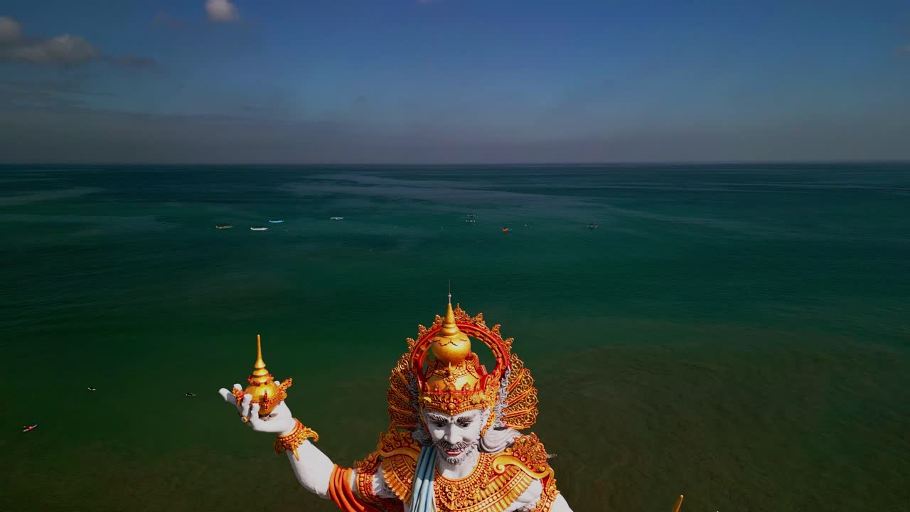 Aerial view of Kuta Beach reveals the grand Baruna statue standing proudly by the shore, symbolizing ocean guardianship while offering a striking cultural landmark against the turquoise waters