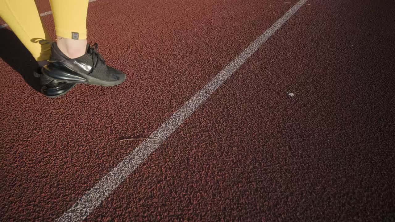 Atleta donna che corre su pista all'aperto in abbigliamento sportivo