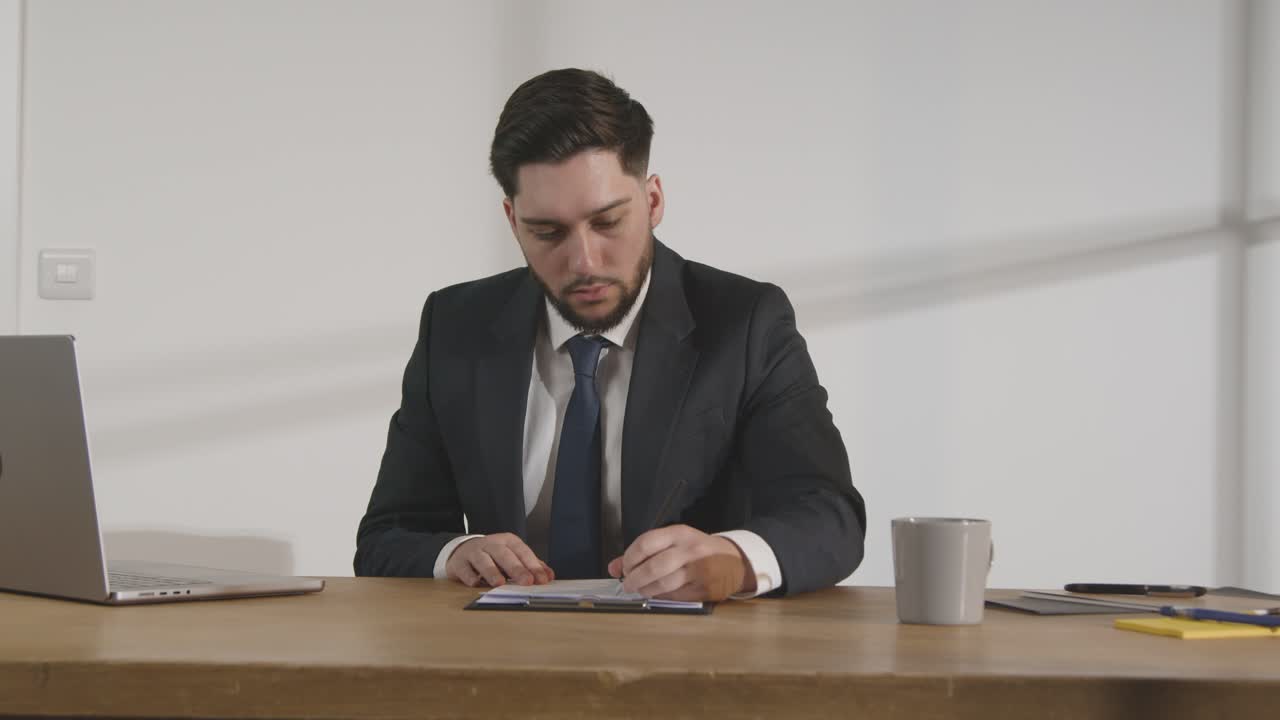 бизнесмен в офисе, просматривающий и делающий пометки в заявлении или резюме на вакансию