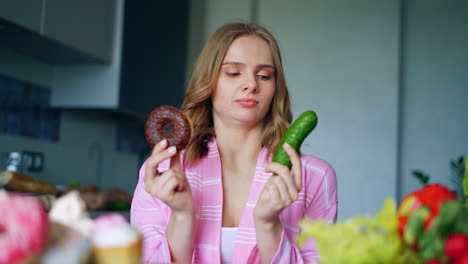 chica bonita eligiendo entre pepino fresco o rosquilla de chocolate