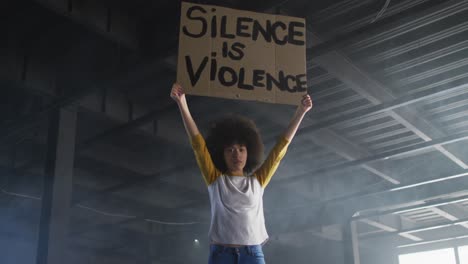 retrato de una mujer afroamericana con un cartel de protesta en un garaje vacío