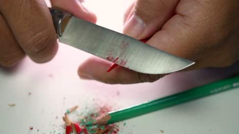 Footage-of-hands-slowly-sharpening-a-pencil-and-some-coloured-pencils-with-a-sharp-knife