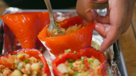 isolated macro view of stuffing red sweet bell peppers with a savory vegan mixture - slow motion