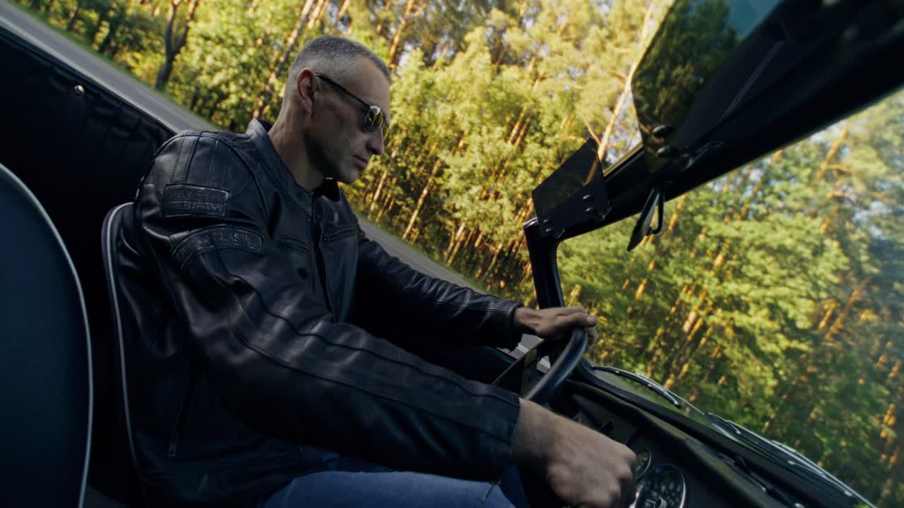 Mann fährt mit einem Cabrio auf einer Waldstraße