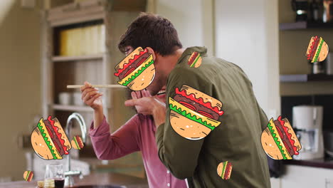 múltiples iconos de hamburguesas cayendo contra una pareja biracial probando comida en la cocina en casa