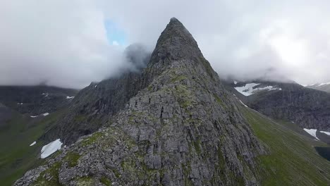 FPV-drone-boldly-ascends-a-mountain-ridge,-surrounded-by-misty-peaks,-unveiling-a-mystical-alpine-world-from-a-thrilling-aerial-perspective
