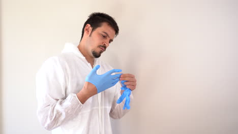 doctor in ppe suit putting on blue latex gloves