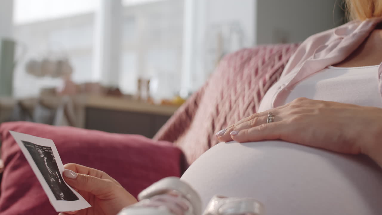 임신 중인 어머니가 초음파 영상을 보고 미소 짓고 있습니다.