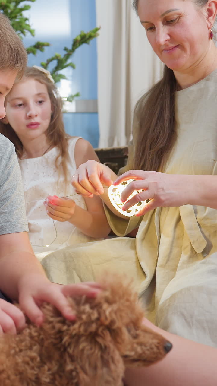 Madre e hijos encendiendo una vela juntos en un salón acogedor; la madre sujeta con cuidado una pequeña vela brillante mientras el niño acaricia a un perro de pelo rizado y la niña observa; luz cálida y suave; tierno vínculo familiar.