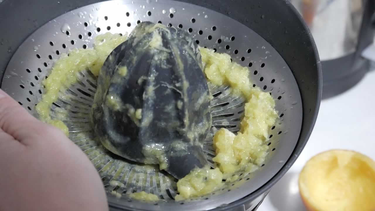 Fersk appelsinjuice presses ut med en håndpresse, med skall som spruter fra frukten