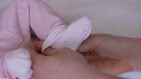 newborn girl is moving legs while young father putting on a sock