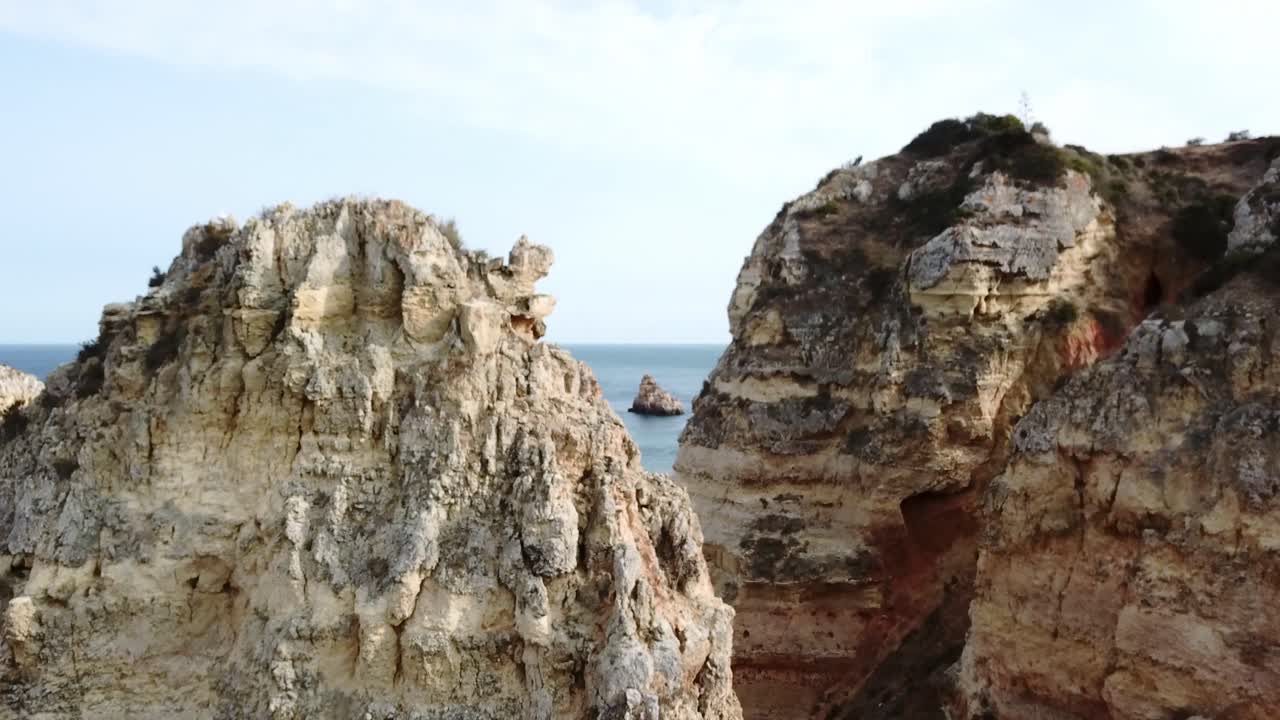 Aerea: Innalzandosi sopra formazioni rocciose calcaree in Algarve, Portogallo, per rivelare barche e scogliere a picco sul mare.
