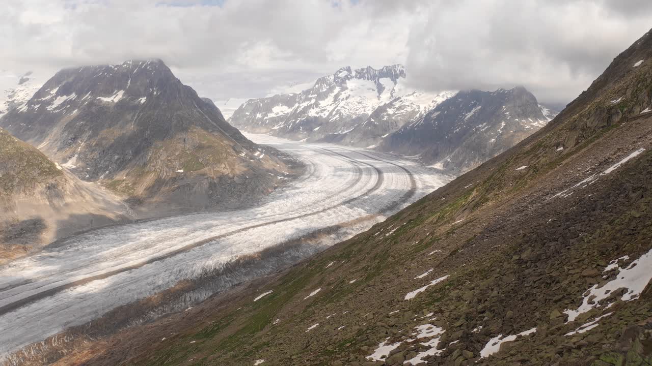 Couple standing on mountain peak with a breathtaking view of Aletsch Arena