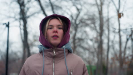 lady in winter outfit jogging briskly through snow-covered outdoor park in urban setting, staying active and warm in cold weather, surrounded by trees with no leaves and chilly urban surrounding