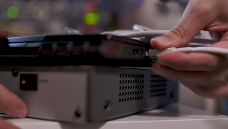 un técnico, dentro de la sala de servidores, inserta un cable en el puerto lan de una computadora portátil en la parte superior de un enrutador