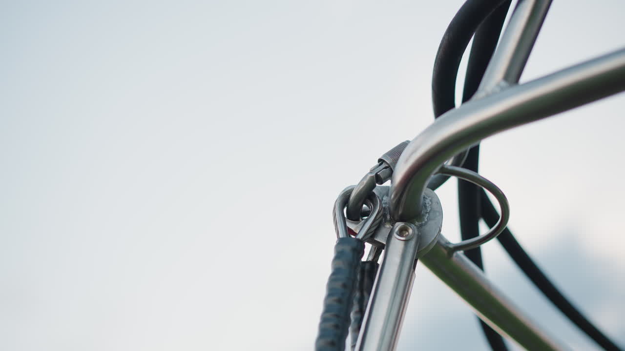 gloved hands tightening bolt on metal frame of hot air balloon burner during flight setup under clear sky close up detail with pipes hoses and connectors visible