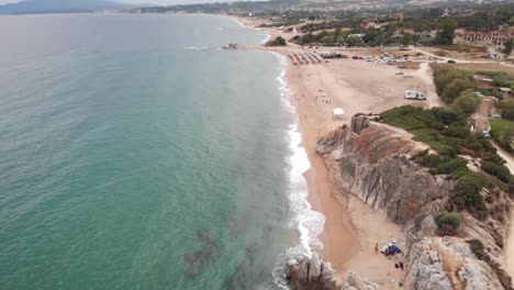 Orbit-Drone-video-waves-at-sandy-beach-people-camping-swimming-summer-day