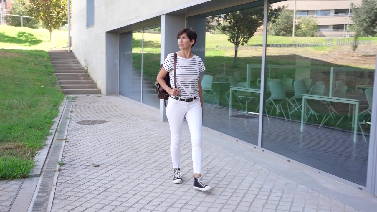 Una persona joven con estilo caminando felizmente en un entorno urbano contemporáneo durante el día.