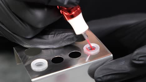 close-up of a tattoo artist preparing red ink for a tattoo or permanent makeup procedure