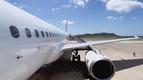 tilt down view from front door of fuselage wing and engine of airplane parked at ibiza balearic island airport with stairs attached on sunny day