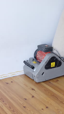 sanding beautiful pine floor with industrial machine, vertical view